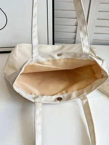 Detail view of cream white tote bag featuring magnetic silver clasp and spacious interior