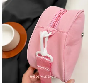 Dettaglio borsa a tracolla in nylon rosa con gancio in plastica bianca e tracolla in tessuto
