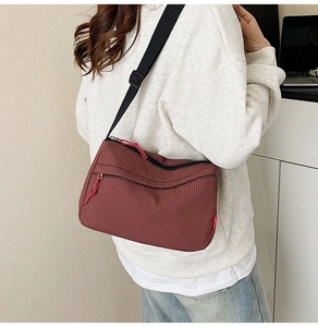 Detail of burgundy checkered nylon crossbody bag with black adjustable shoulder strap