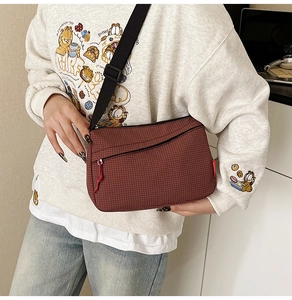 Brown checkered canvas crossbody bag with adjustable black strap and red fashion tag