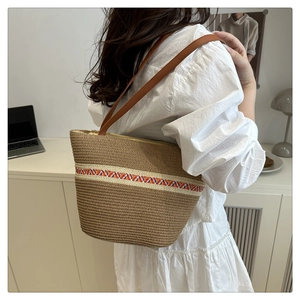 Détail d'un sac cabas en paille avec ruban ethnique coloré et fines anses en cuir marron