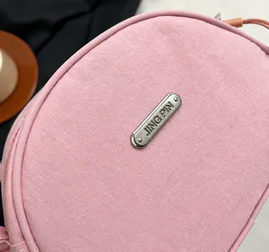 Dettaglio borsa in nylon rosa con placca logo in argento e incisione JING PIN