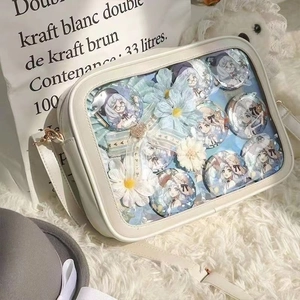 Détail d'un sac Ita JK blanc crème avec fenêtre transparente, badges anime et décoration