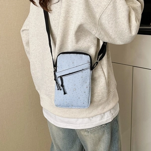 Light blue crossbody phone bag with star pattern and adjustable black strap for travel