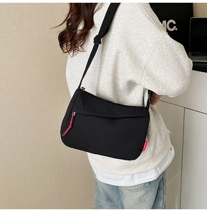 Detail showing back view of black nylon crossbody bag with red FASHION label on model