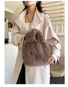 Détail d'un sac à main en fausse fourrure marron foncé avec un trench-coat beige