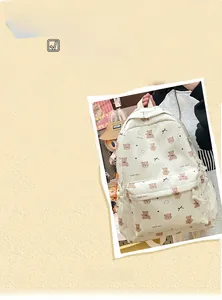Detail of cream backpack featuring brown cartoon bear pattern and front zipper pocket