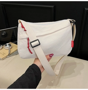 Detail view of white nylon shoulder bag with textured fabric and red fashion label