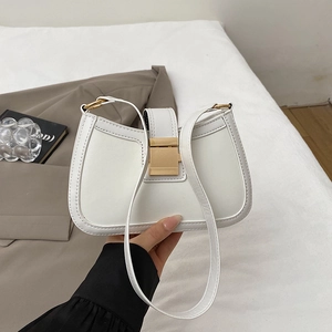 Dettaglio della borsa a sella in pelle bianca con fibbia dorata e texture liscia opaca