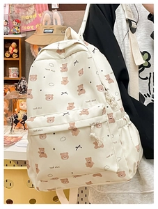 Close-up detail of cream canvas backpack featuring cute brown bear print and front pocket
