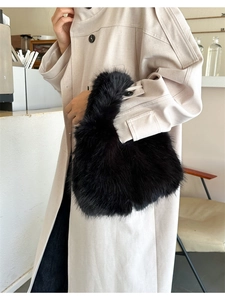 Détail du sac à main noir en fausse fourrure porté par un mannequin en trench beige