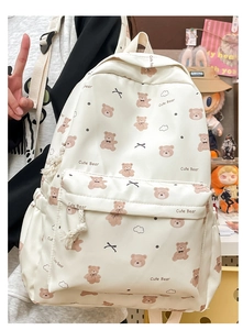 Detail of white canvas backpack featuring cute brown bear patterns and multi-pocket design