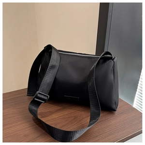 Close-up of adjustable fabric strap and silver metal zipper on black nylon crossbody bag