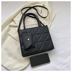 Close-up of black quilted handbag with mini coin purse and detachable shoulder strap