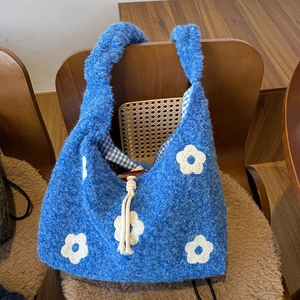 Detail of blue plush tote bag featuring daisy patterns, wooden button, and drawstring closure