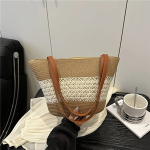 Sac cabas bicolore en paille avec anses en cuir marron sur fond de canapé minimaliste