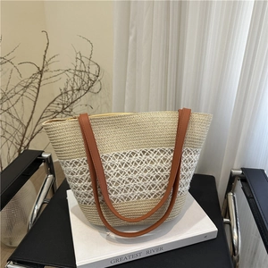 Grand sac cabas en paille avec anses brunes et design en maille losange sur une chaise