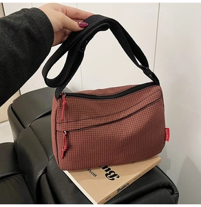 Detailed close-up of dark red nylon crossbody bag showing the fine plaid texture and tag