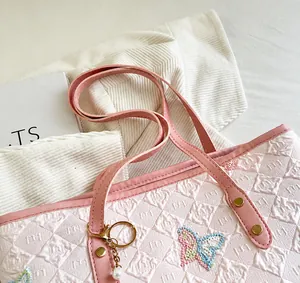 Close-up of pink tote bag featuring embossed textures and embroidered butterfly patch