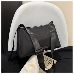 Detailed macro view of the sleek black nylon crossbody bag with silver zipper closure