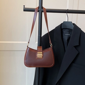 Dettaglio borsa a sella in pelle marrone con fibbia dorata quadrata e cuciture precise