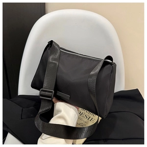 Detail of minimalist black crossbody bag with adjustable wide fabric strap and silver zipper