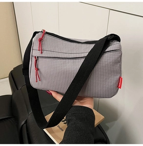 Close-up of gray grid texture nylon bag with red cord zippers and fashion label