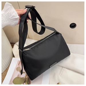 Detail of minimalist black nylon crossbody bag featuring silver zipper and adjustable strap
