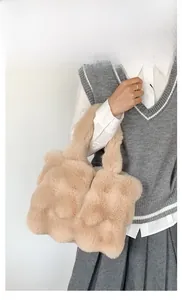 Detail of soft beige plush tote bag handle and fluffy texture in a model show