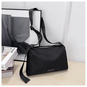 Close-up of a black nylon crossbody bag with adjustable strap and metal logo detail