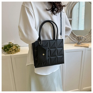 Detail of a black quilted handbag with double handles and a matching mini attachment bag