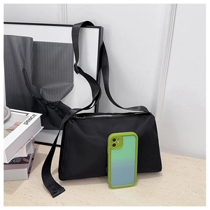 Close-up of black nylon shoulder bag with wide strap next to a phone case for size