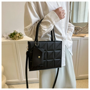 Detailed view of a black quilted tote bag with a matching small charm pouch