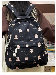 Close-up of black backpack featuring cute bear prints and front zipper pocket detail