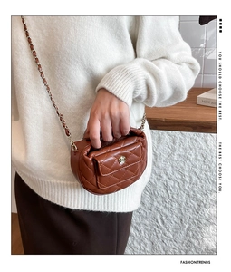Detail of a brown quilted mini crossbody bag with a metal flower clasp and chain strap