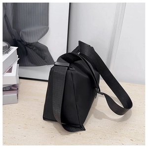 Detail view of black nylon crossbody bag with wide fabric strap and clean stitching