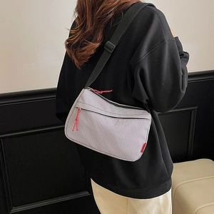 Minimalist grey nylon crossbody bag with adjustable strap worn by model in casual style