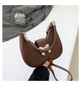 Détail d'un sac demi-lune marron avec boucle nœud argentée et fermeture zippée
