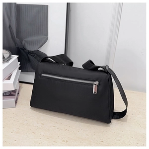 Detail view of smooth silver metal zipper and nylon strap on black crossbody bag
