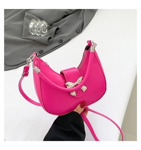 Gros plan d'un sac demi-lune fuchsia avec boucle nœud argentée et fermeture éclair