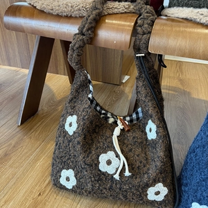 Winter brown fleece drawstring tote bag with white daisy patterns and cozy wood seat background