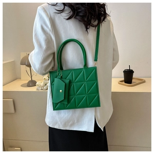 Detail of green quilted crossbody bag with matching mini pouch and gold hardware accents