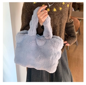 Close-up of light blue plush tote bag in soft faux fur with thick handles and fluffy texture
