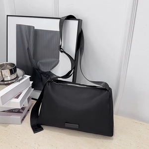 Minimalist black nylon crossbody bag with adjustable wide strap and silver zipper closure
