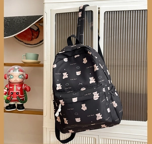 Detail of cute pink bear pattern and text on waterproof black nylon backpack surface