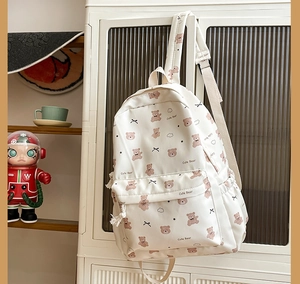 Detail of cute bear printed white canvas backpack with front pocket and drawstring side