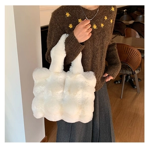 Detailed view of a soft white plush tote bag carried by a model in a warm cafe setting