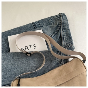 Flachbild von beiger minimalistischer Umhängetasche kombiniert mit Jeansjacke und Buch
