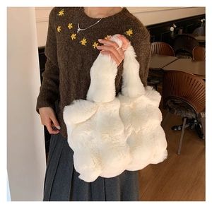 White faux fur tote bag styled with a brown coat in a cozy cafe indoor setting