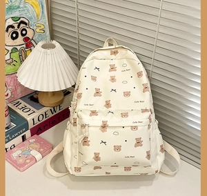 Close-up of cute cartoon bear print and bow detail on beige student backpack